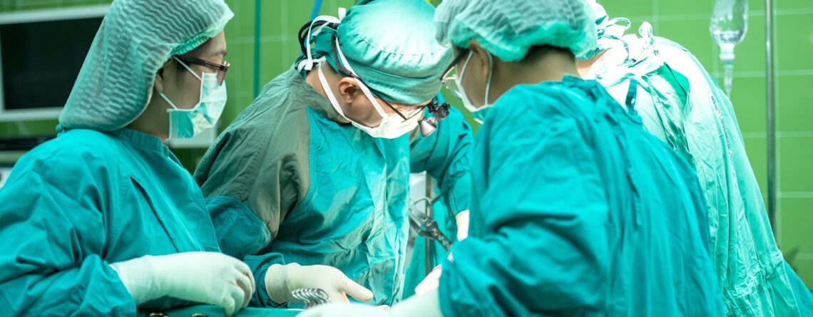 four doctors performing surgery in operation theatre with scissors and forceps